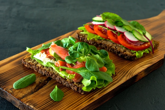 Légumes et saumon fumé en treillis de sandwichs ouverts, tomates sur un bureau en bois. Petit-déjeuner sain