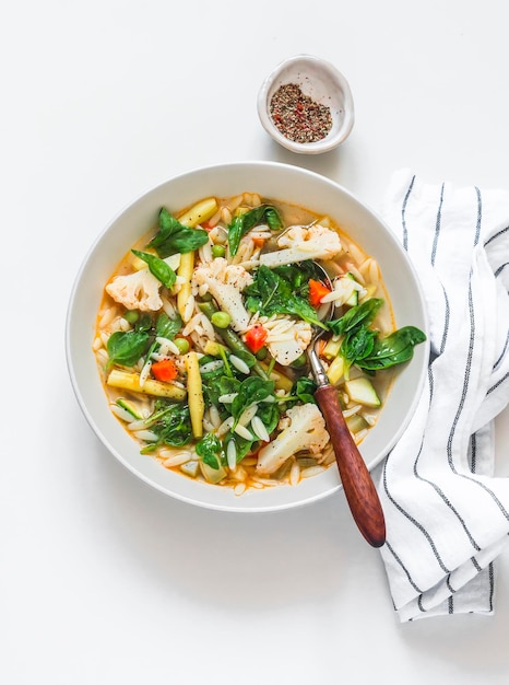 Légumes et soupe végétarienne de pâtes orzo sur fond clair vue de dessus