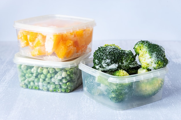 Légumes surgelés. Brocoli, pois et citrouille surgelés dans des boîtes en plastique sur table grise