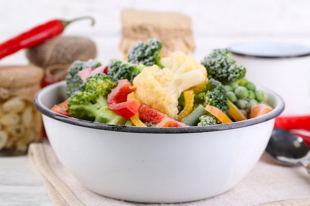 Légumes surgelés dans un bol sur une serviette sur fond de table en bois