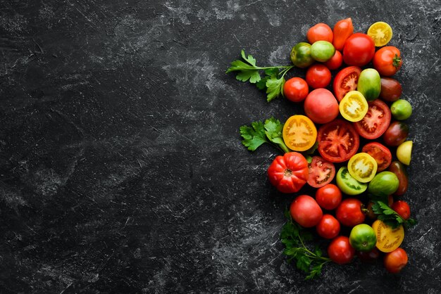 Légumes Tomates colorées fraîches Sur fond de pierre noire Vue de dessus Espace libre pour votre texte