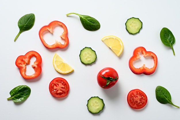 Légumes en tranches et épinards sur fond blanc