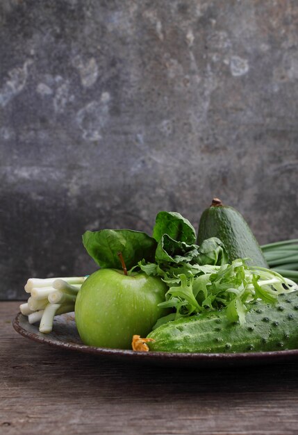 Légumes verts: concombre, laitue, oignon, avocat, pomme sur fond vieux