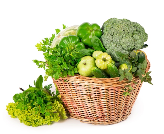 Légumes verts dans un panier en osier - brocoli, courgettes, concombres, pastèque, raisins, poivrons, pommes et laitue