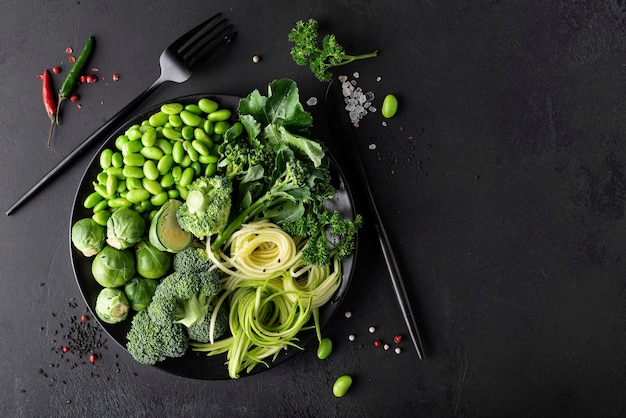 Légumes verts frais aux herbes et épices sur un fond sombre