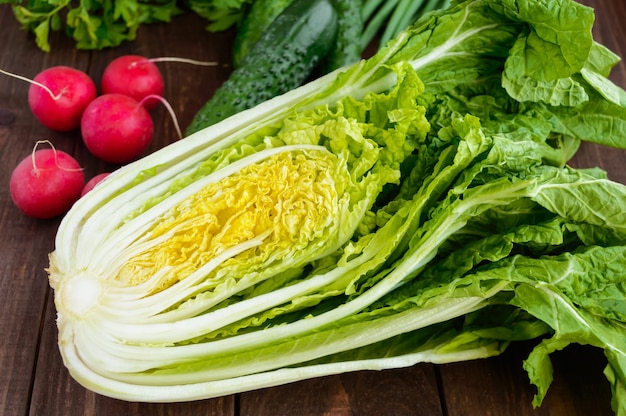 Légumes verts frais (chou, concombres), oignons verts, persil et radis sur fond de bois. Pour les salades.