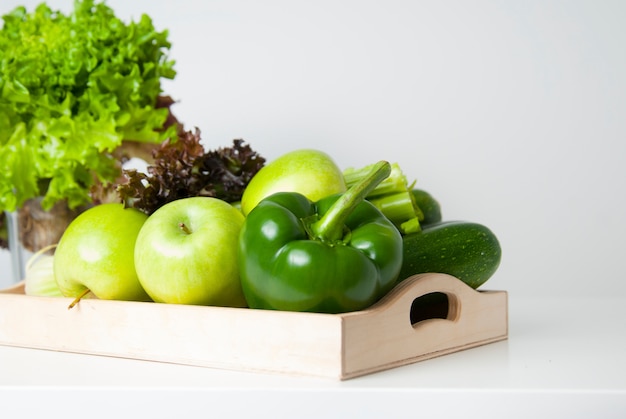 Légumes verts frais et fruits dans une boîte en bois.