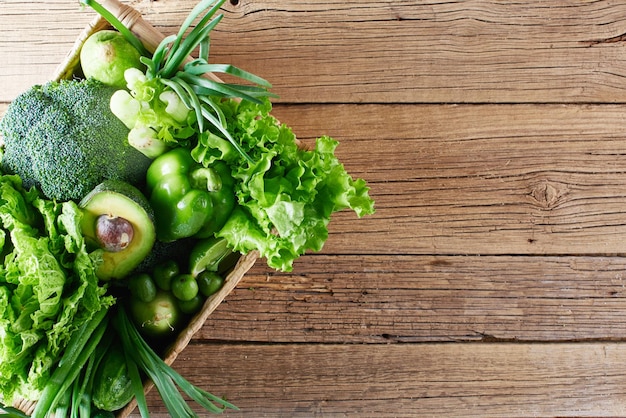 Légumes verts et fruits et légumes verts dans un panier en osier marron sur fond de bois. Notion de saine alimentation