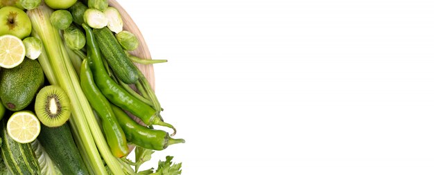 Légumes verts sur une plaque en bois sur fond blanc