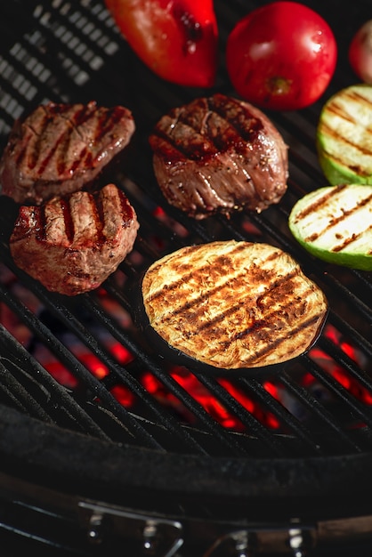 Photo légumes et viande grésillant sur le gril avec des flammes, gros plan