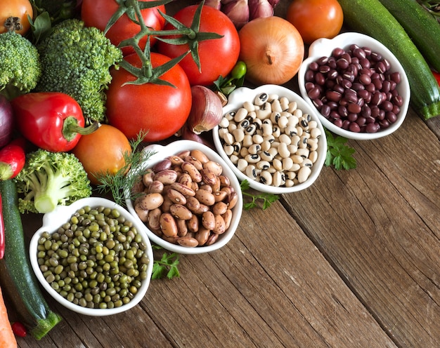 Légumineuses dans des bols et légumes sur bois se bouchent avec un espace de copie