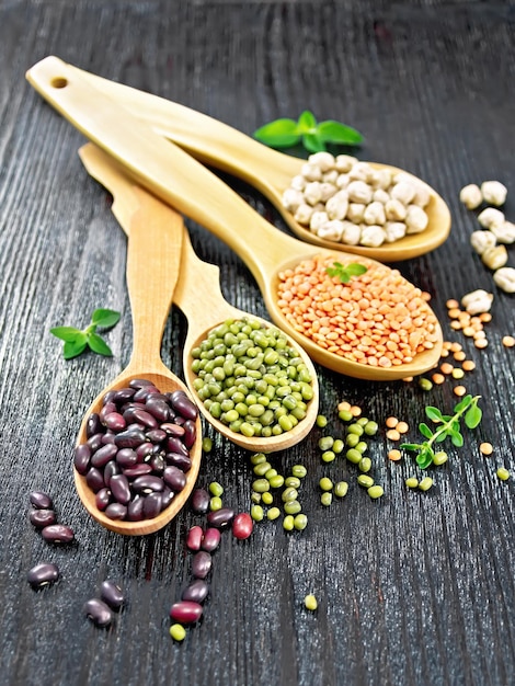 Lentilles aux pois chiches et haricots dans des cuillères sur planche de bois