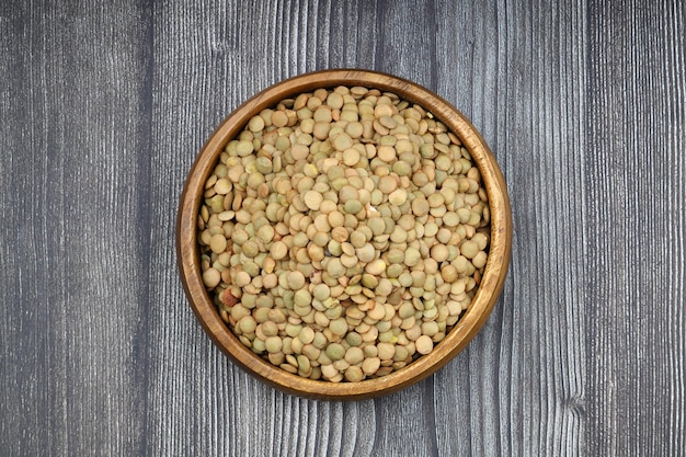Lentilles vertes dans un bol en bois sur un fond de table en bois Espace de copie en vue supérieure Placé à plat