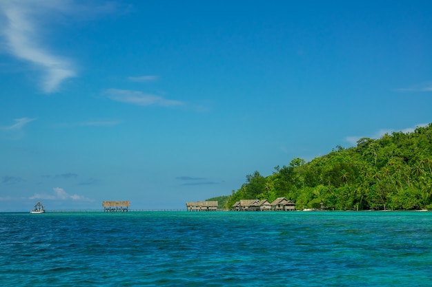 Îles indonésiennes. Ciel bleu. Côte de l'océan et de la jungle. Cabanes sur pilotis dans l'eau