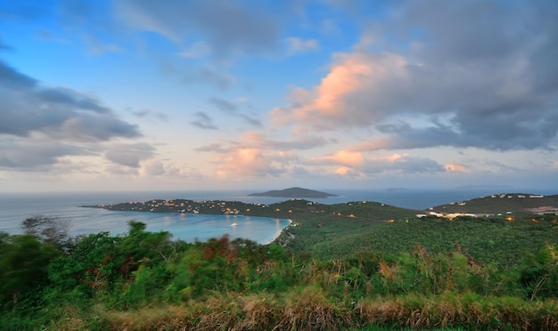 Îles Vierges St Thomas vue sur la montagne au coucher du soleil avec des nuages colorés, des bâtiments et un littoral de plage.