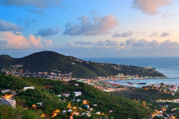 Îles Vierges St Thomas vue sur la montagne au coucher du soleil avec des nuages colorés, des bâtiments et un littoral de plage.