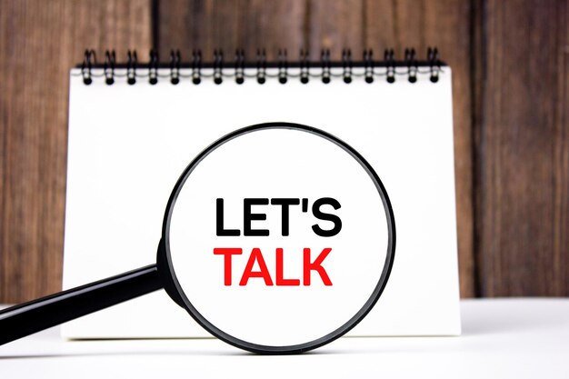 LET'S TALK concept de texte à travers une loupe sur un bloc-notes