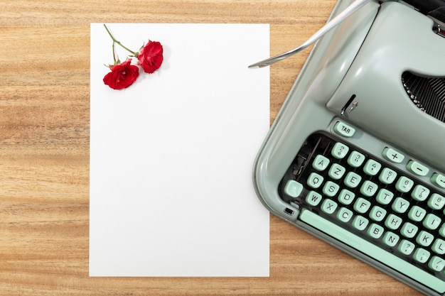 Lettre d'amour. Bureau avec papier vierge, machine à écrire rétro, pétales et roses rouges