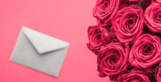 Lettre d'amour et livraison de fleurs le jour de la Saint-Valentin bouquet de roses de luxe et carte sur fond rose pour la conception de vacances romantiques