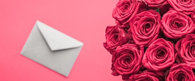 Lettre d'amour et livraison de fleurs le jour de la Saint-Valentin bouquet de roses de luxe et carte sur fond rose pour la conception de vacances romantiques