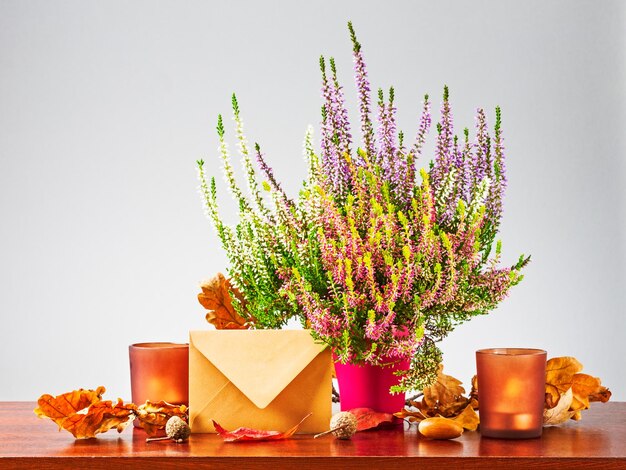 Lettre d'automne. Nature morte avec enveloppe fermée, fleurs de bruyère, feuilles de chêne sèches et bougies