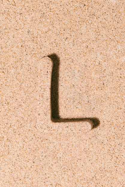 Photo lettre l du sable isolé sur le concept de sable de plage de l'alphabet d'été