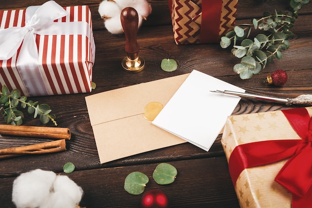 Lettre vide avec une plume sur le vieux fond en bois décoré des objets de Noël