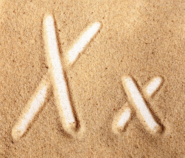 Lettre X alphabet manuscrit anglais dans le sable