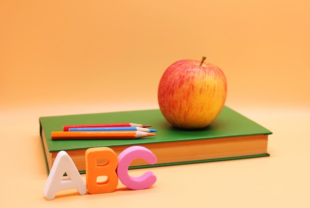Lettres de l'alphabet anglais ABC à côté de livre et de pomme.