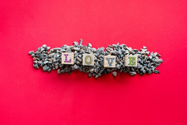 Photo les lettres amour de différentes couleurs sur le cube en bois qui se trouve sur un tas de petites pierres ou de cailloux concept du jour de l'amour ou de la saint-valentin vue de dessus gros plan espace de copie pour le design et le texte