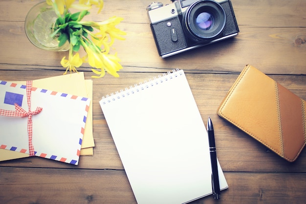 Lettres, appareil photo, stylo, papier, bloc-notes et fleur sur table en bois