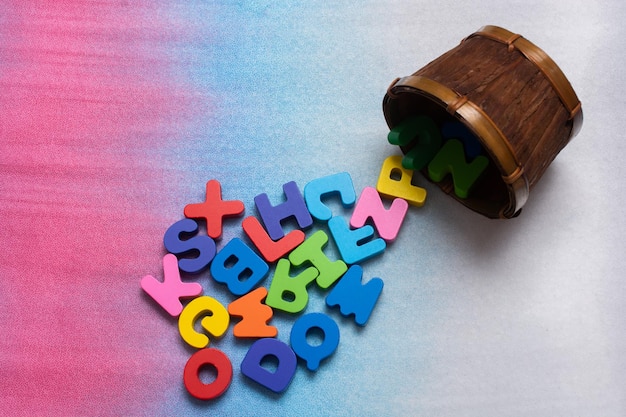 Lettres en bois colorées dans un récipient sur un fond coloré