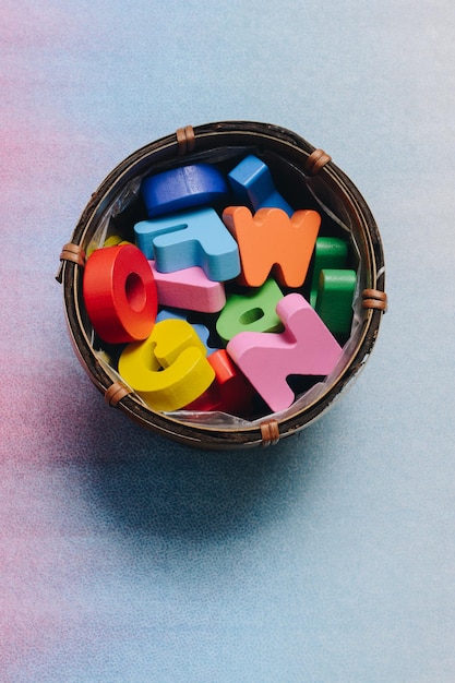 Lettres en bois colorées dans un récipient sur un fond coloré