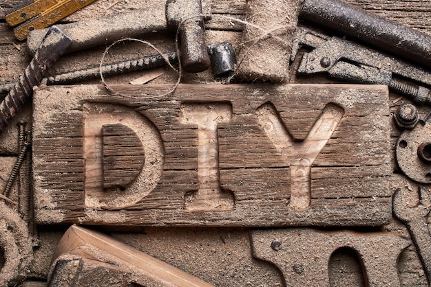 Lettres de bricolage sur une planche de bois sur fond d'outils de travail. Faites-le vous-même.