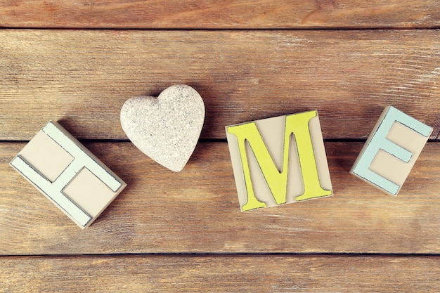 Photo lettres décoratives formant le mot home avec coeur décoratif sur fond en bois