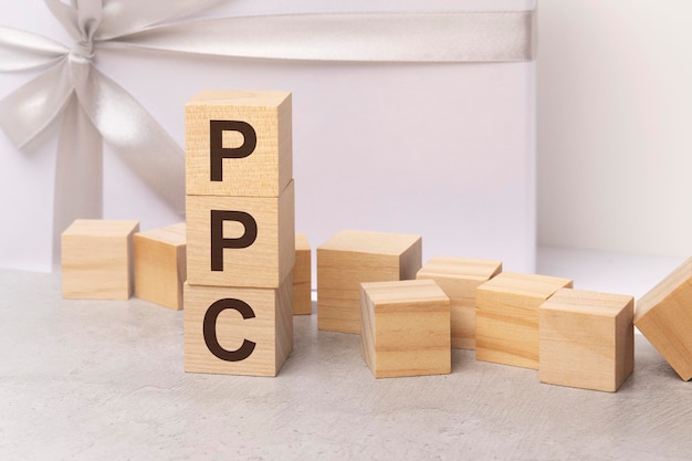 Lettres ppc sur le concept de cubes en bois sur fond de boîte cadeau léger comme d'habitude espace d'image de concept pour le texte en vue de face droite ppc court pour Pay Per Click