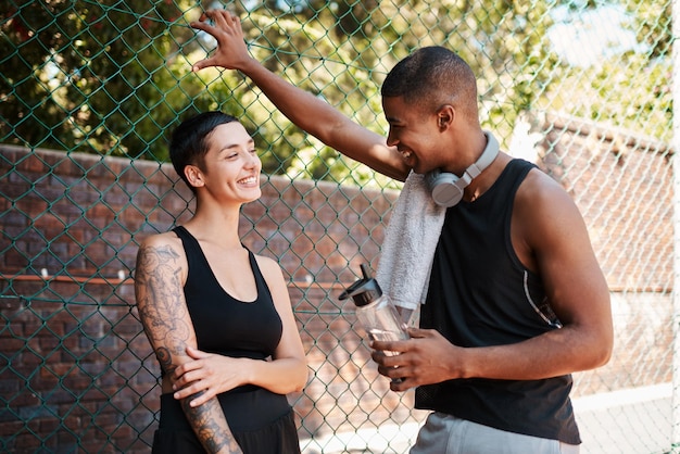 Leurs conversations sont toujours joyeuses Photo de deux jeunes sportifs discutant entre eux contre une clôture à l'extérieur