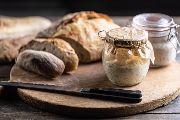 Levain de seigle mûri dans un bocal avec du pain frais sur une planche à découper