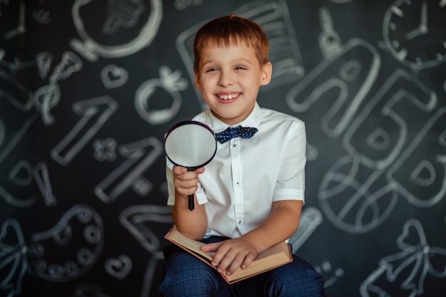 Élève de l'école primaire garçon avec une loupe dans ses mains