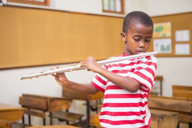 Élève mignon jouant de la flûte dans la salle de classe