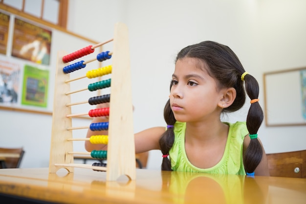 Élève mignon utilisant abacus dans la salle de classe