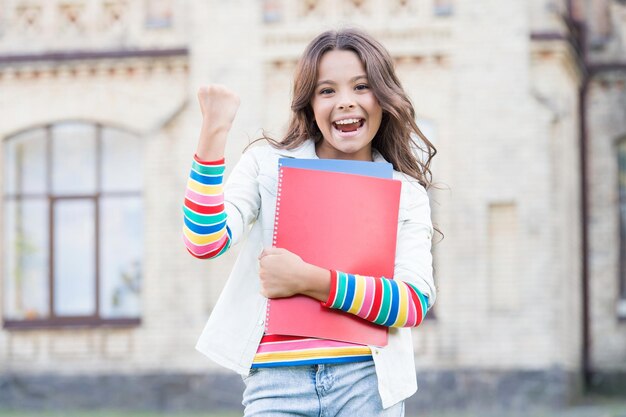 Élève qui réussit Éducation moderne Enfant souriant fille écolière tenir des cahiers d'exercices manuels pour étudier Éducation pour les enfants surdoués Suivre un cours supplémentaire pour un apprentissage plus approfondi Éducation scolaire