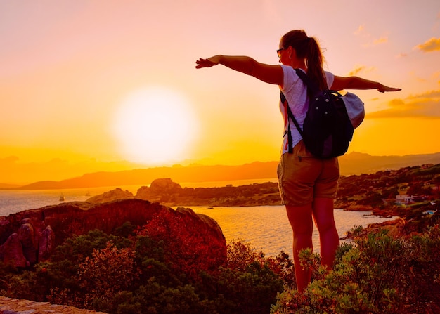 Lever ou coucher du soleil et jeune fille à Baja Sardinia de Costa Smeralda en mer Méditerranée sur l'île de Sardaigne en Italie. Femme et Sardaigne en été.