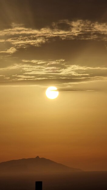 Le lever et le coucher du soleil sur la silhouette de la montagne Arrière-plan Un rayon de soleil doré éclaire l'horizon Vertical