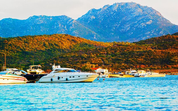 Lever ou coucher du soleil avec des yachts à Porto Rotondo sur la Costa Smeralda en mer Méditerranée en Sardaigne, île d'Italie. Bateau en Sardaigne en été. Paysage de la province d'Olbia. Technique mixte.