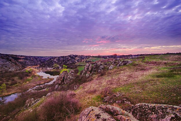 Lever du soleil au canyon avec rivière, collines et ciel dramatique avec réflexion