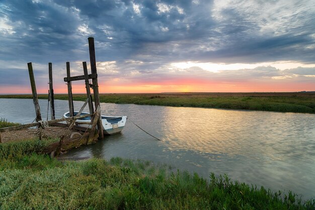 Lever du soleil sur un bateau amarré à une ancienne jetée en bois à Thornham