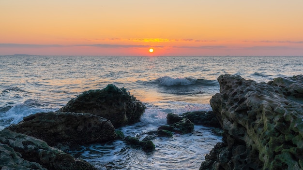 Lever du soleil coloré sur un bord de mer rocheux