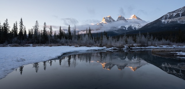 Lever du soleil d'hiver avec des montagnes se reflétant dans l'eau