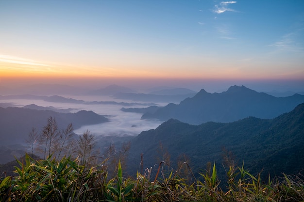 Le lever du soleil à la montagne avec le brouillard et les nuages le recouvrent